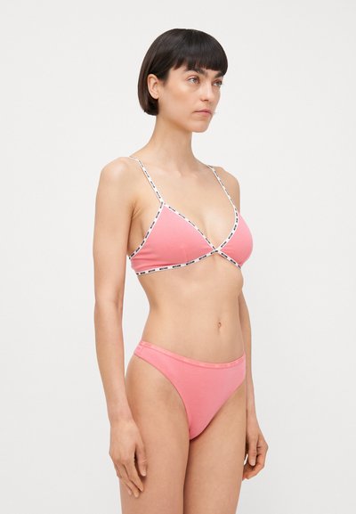 Rozā trīsstūrveida krūšturis un saskaņojoši bikini apakšdaļa. Mīksta auduma ar plānām siksnām un logotipa joslu gar malām. Vienkāršs un pieguļošs dizains.