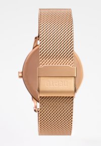 Rose gold mesh ur med et rundt urkasse og struktureret rem. Låsen er præget med mærkenavnet "neptoto."