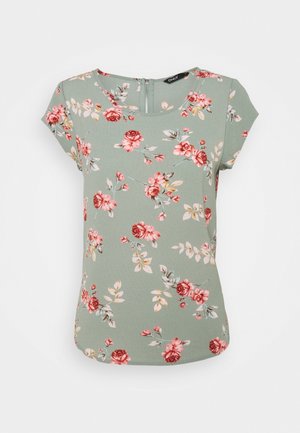 Grüne Kurzarmbluse mit rundem Ausschnitt, Rückenreißverschluss und pink-rotem Blumenmuster, das über den Stoff verteilt ist.