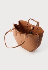 Sac fourre-tout en cuir fauve avec deux poignées, intérieur spacieux et une poche zippée. Texture lisse et forme structurée pour un accès facile.