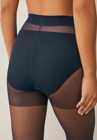 Højtaljet sort formgivende undertøj med et gennemsigtigt mesh-panel øverst. Glat tekstur med en tætsiddende silhuet, der går ned til lårene.