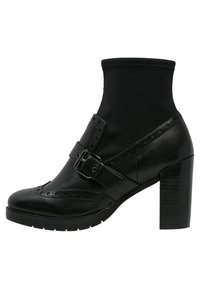 Botines negros con un tacón alto y grueso, material de cuero, parte superior elástica tipo calcetín, hebilla decorativa y detalles de brogue en la puntera.