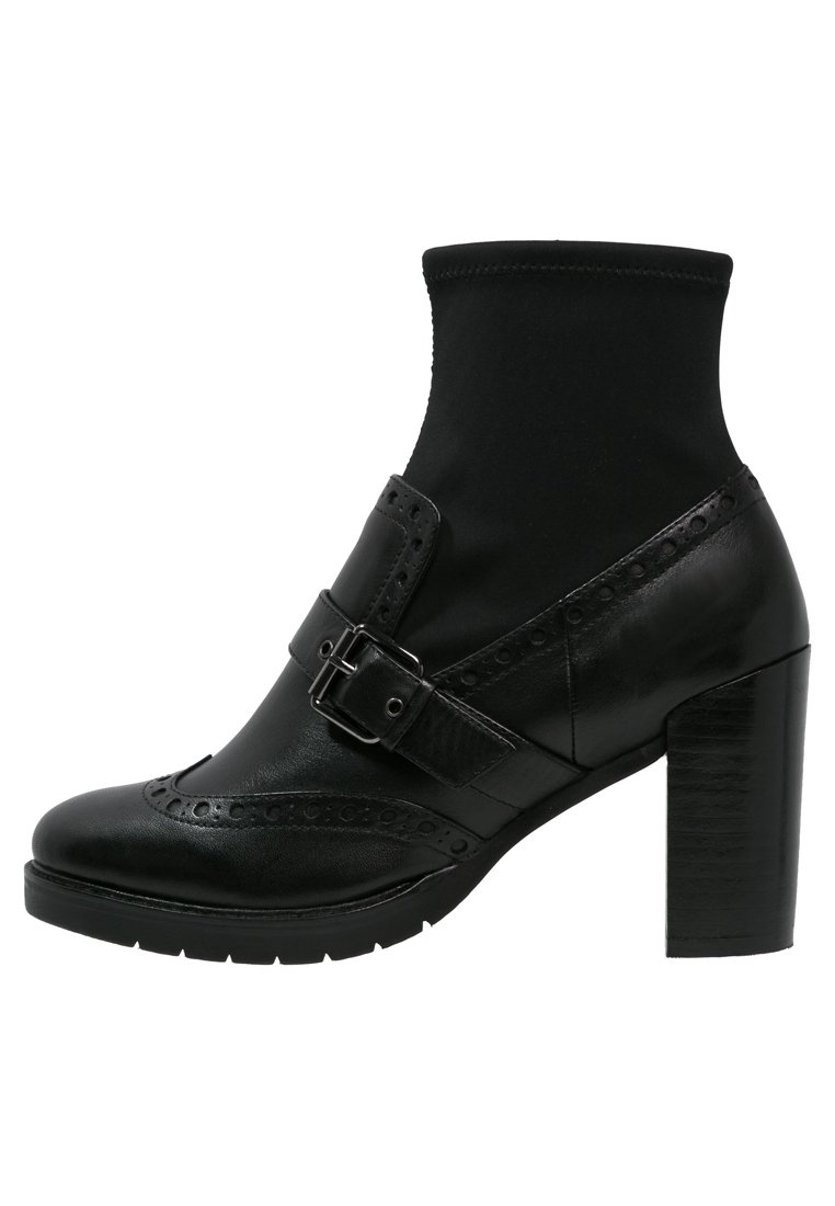 Botines negros con un tacón alto y grueso, material de cuero, parte superior elástica tipo calcetín, hebilla decorativa y detalles de brogue en la puntera.