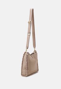 Borsa beige con una rifinitura morbida e texturizzata, tracolla regolabile e tasca frontale. Presenta hardware dorato e un design strutturato ma flessibile.