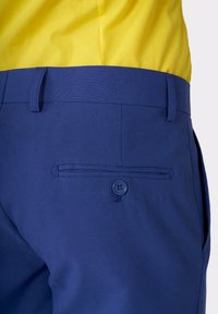 Pantaloni blu realizzati in tessuto morbido, con chiusura a bottone e una tasca posteriore con un singolo bottone. La vita è piatta.