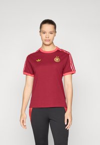 Maillot court à manches courtes bordeaux avec des accents roses, doté d'un col rond, de trois bandes blanches sur les épaules et d'un logo sur la poitrine.