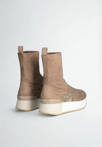 Stivaletti in suede marrone con suola piatta bianca, caratterizzati da un motivo a stella con strass e un motivo intrecciato sul tacco.