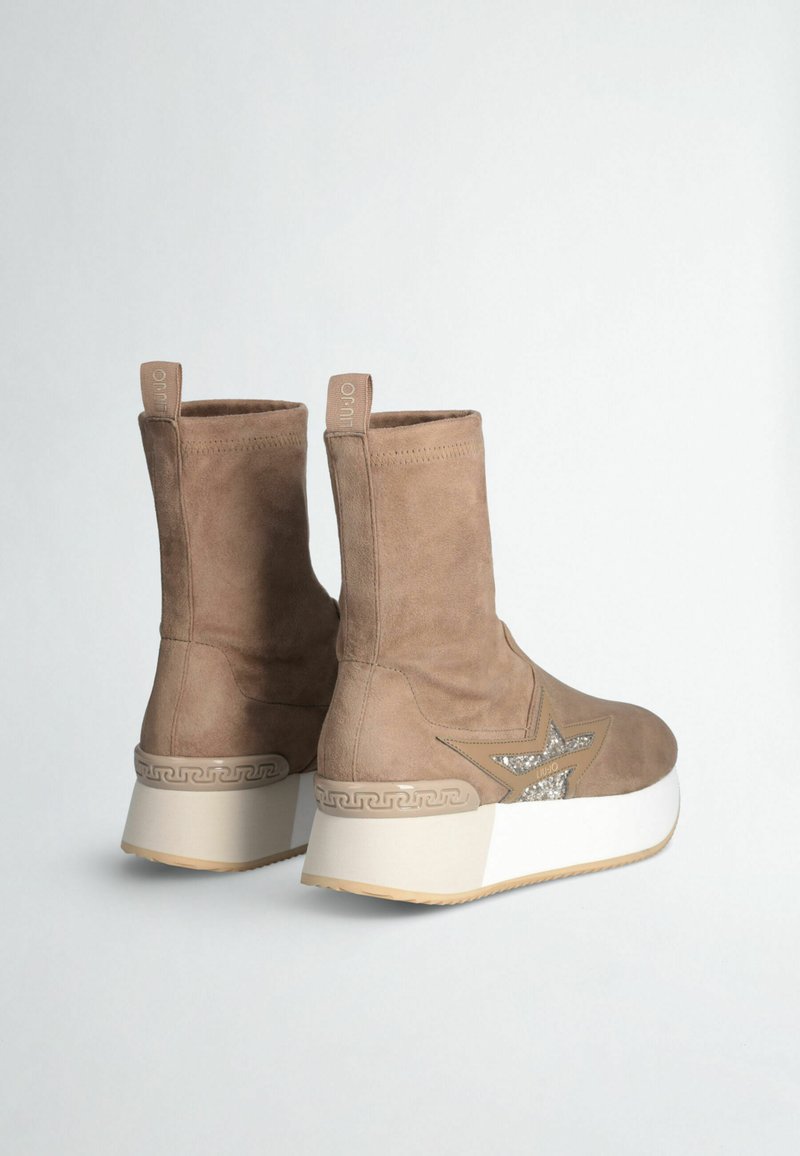 Bottes de cheville en suédine marron avec une semelle plateforme blanche, présentant un design en étoile orné de strass et un motif tissé sur le talon.