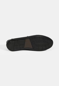 Schwarze Schuhsohle mit strukturiertem Gummibelag, der ein geometrisches Muster und einen zentralen braunen Akzent aufweist. Flaches Design für Stabilität.