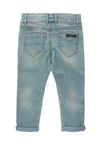 Světle modré džínové kalhoty s přiléhavým střihem, zadními kapsami a ohrnutými nohavicemi. Tkanina má mírně vybledlý vzhled a viditelné švy.