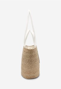 Sac en osier tissé marron avec deux poignées en cuir blanc et un intérieur en tissu crème, vu de côté sur un fond blanc.