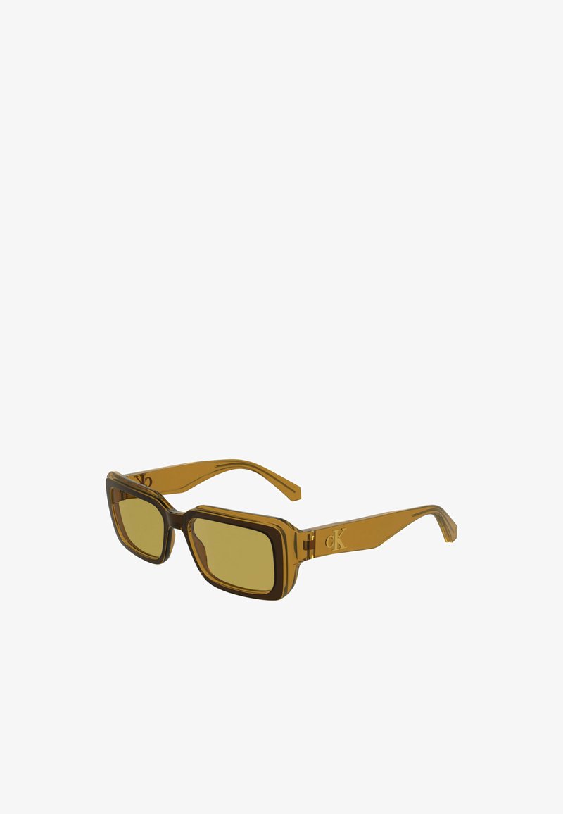 Ορθογώνια γυαλιά ηλίου με διαφανή καφέ σκελετό και φακούς με κίτρινη απόχρωση. Διαθέτουν μια διακριτική λογότυπο στο πλάι. Λείος υφή.