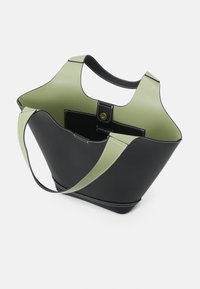 Černá a světlě zelená taška přes rameno s širokými uchy, otevřeným vrchem a vnitřní kapsou se zavíráním na patentku, viditelná na bílém pozadí.