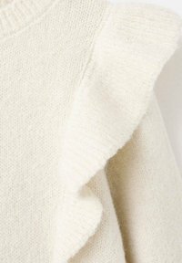 Bílý pletený svetr s jemnou texturou, s žebrovaným límcem a volánkovým detailem na rameni pro zvýraznění.