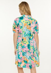 Abito floreale con colori vivaci come turchese, rosa e giallo. Maniche corte a sbuffo, vita elastica e design a strati della gonna.