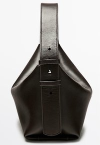 Tmavě hnědá kožená kabelka s jedinečným skládacím tvarem, širokým popruhem a jemnými šicími detaily. Má zapínání na cvoček a kovové doplňky.