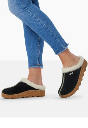 Black suede clogs with a fluffy white faux fur lining and textured brown rubber sole. Features exposed stitching and slip-on design.