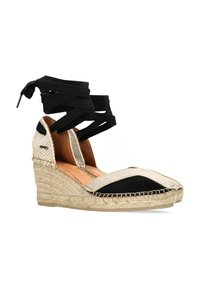 Le zeppe espadrille nere e beige presentano una suola in juta intrecciata, una parte superiore in tessuto con un laccio alla caviglia in raso nero e una punta arrotondata.