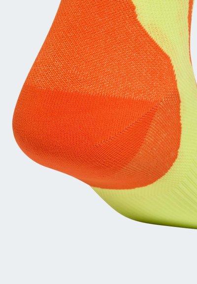 Calcetín deportivo en un vibrante color naranja y amarillo, que presenta un diseño de punto texturizado con refuerzo en el talón y soporte para el arco.