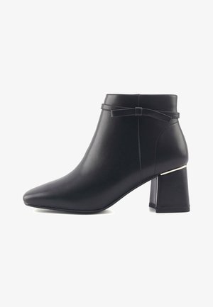 Sort læder ankelstøvle med spids tå, bred blokhæl og en dekorativ sløjfe på siden. Glat tekstur og minimalistisk design.