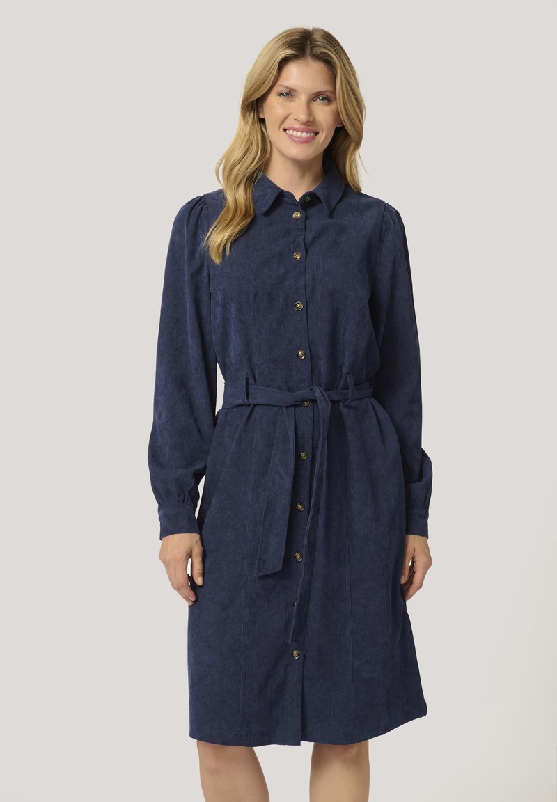 Robe chemise bleu marine en tissu texturé, dotée de manches longues, d'une fermeture à boutons à l'avant et d'une ceinture nouée à la taille. Des boutons dorés ajoutent une touche de détail.