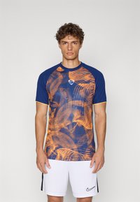 Blue and orange printed athletic shirt with short sleeves and round neckline; features a logo on the chest and a textured design.