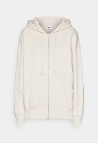 Ljust beige zip-up hoodie gjord av mjuk bomull. Har en framficka, dragsko i huvan och en liten vit logotyp på bröstet.