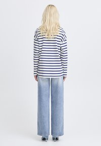 Langærmet top med striber i hvid og marineblå, kombineret med lyseblå jeans med vide ben, der har en afslappet pasform og tekstureret stof.