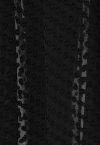 Black fabric with a textured pattern of raised, round dots. The surface appears slightly sheer, with a smooth drape and soft texture.