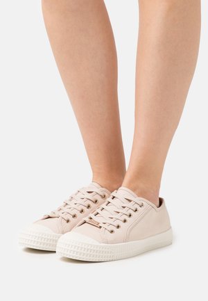 Light pink canvas sneakers with white rubber soles, featuring gold eyelets and laces, rounded toe, and textured tread detailing.
