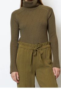 Olivově zelený žebrovaný rolák se dlouhými rukávy, s přiléhavým střihem a strukturovaným úpletem. Doplněný o kalhoty s nastavitelným pasem ve stejné barvě.