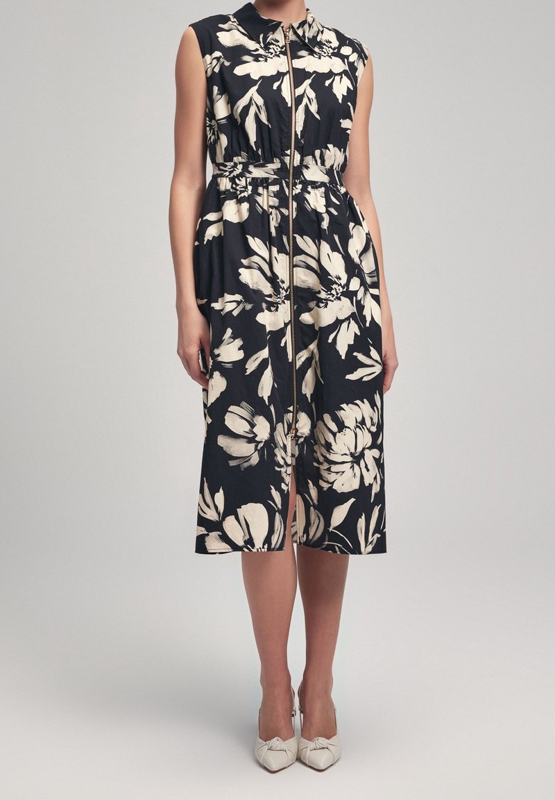Floral-patterned, sleeveless dress featuring a collared neckline, zip closure, and an elastic waist, in navy with cream flowers.