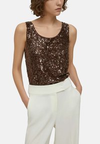 Top marrone a canotta con paillettes e scollatura arrotondata, abbinato a pantaloni bianchi a vita alta con due bottoni in vita.