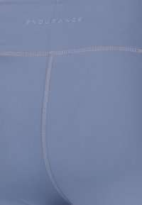Blå atletiska shorts med en slät textur, featuring en figurnära design och söm-detaljer. Logotypen "ENDURANCE" syns på midjebandet.