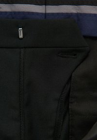 Pantaloni da ciclismo neri con una texture liscia e elastica. Caratterizzati da una cerniera metallica, cuciture a contrasto e un design elegante per il comfort.