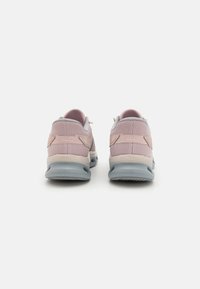 Zapatillas de deporte rosas claras con una parte superior de malla texturizada, acentos grises y una suela acolchada. Presenta una forma redondeada y una lengüeta en el talón.