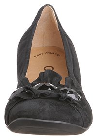 Svart mockaskon med spetsig tå, rynkig tyg framtill och dekorativ svart accent. Medium klack med en texturerad sula.