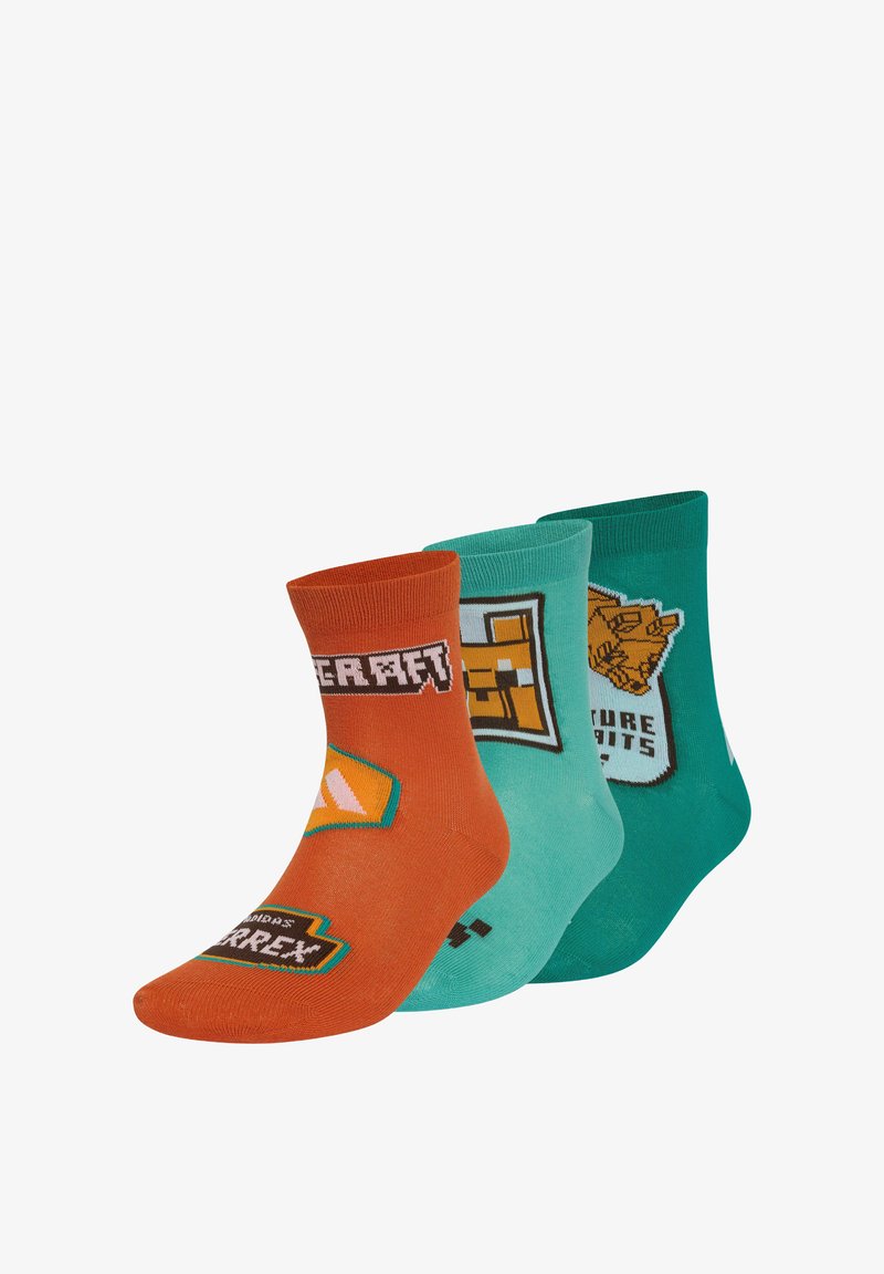 Trois paires de chaussettes colorées avec pixel art et logos sur le thème de Minecraft en nuances d'orange, turquoise et vert, disposées côte à côte.