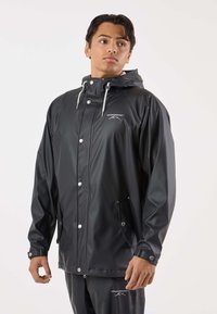 Schwarze wasserdichte Jacke aus glänzendem Material mit Kapuze, Druckknöpfen, verstellbaren Kordeln und Fronttaschen.