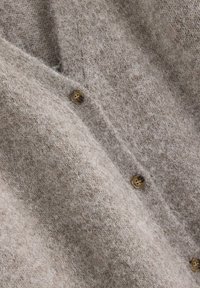 Lysebrun cardigan lavet af blødt, tekstureret stof med dyb V-hals og runde brune knapper langs fronten.