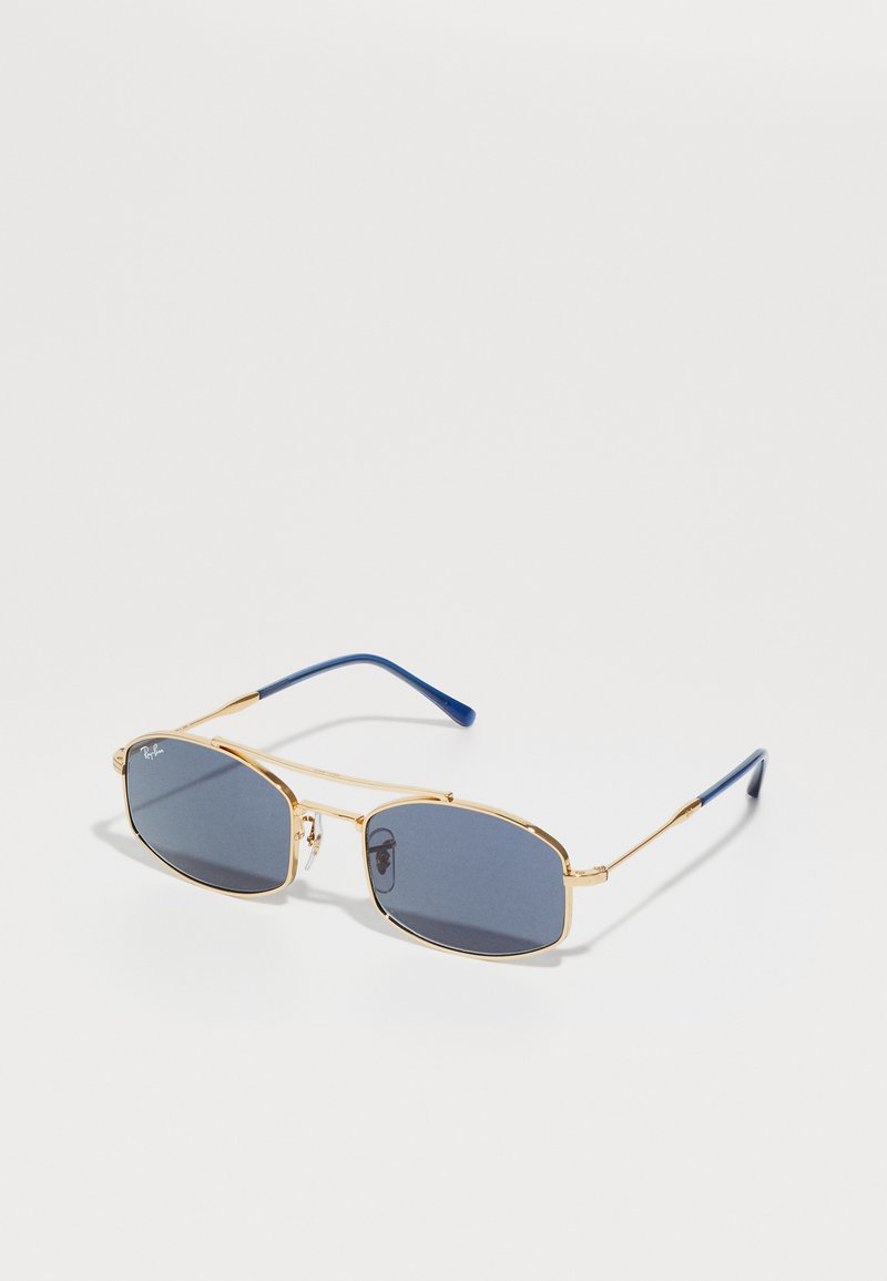 Óculos de sol de metal dourado com lentes escuras ovais e pontas de hastes azuis em plástico. Design simplista com armações estreitas e uma marcação discreta.