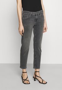 Szare jeansy dżinsowe o średnim stanie i prostych nogawkach, z standardowymi kieszeniami i lekko wyblakłą fakturą. W zestawie z czarnymi sandałami na paski na obcasie.