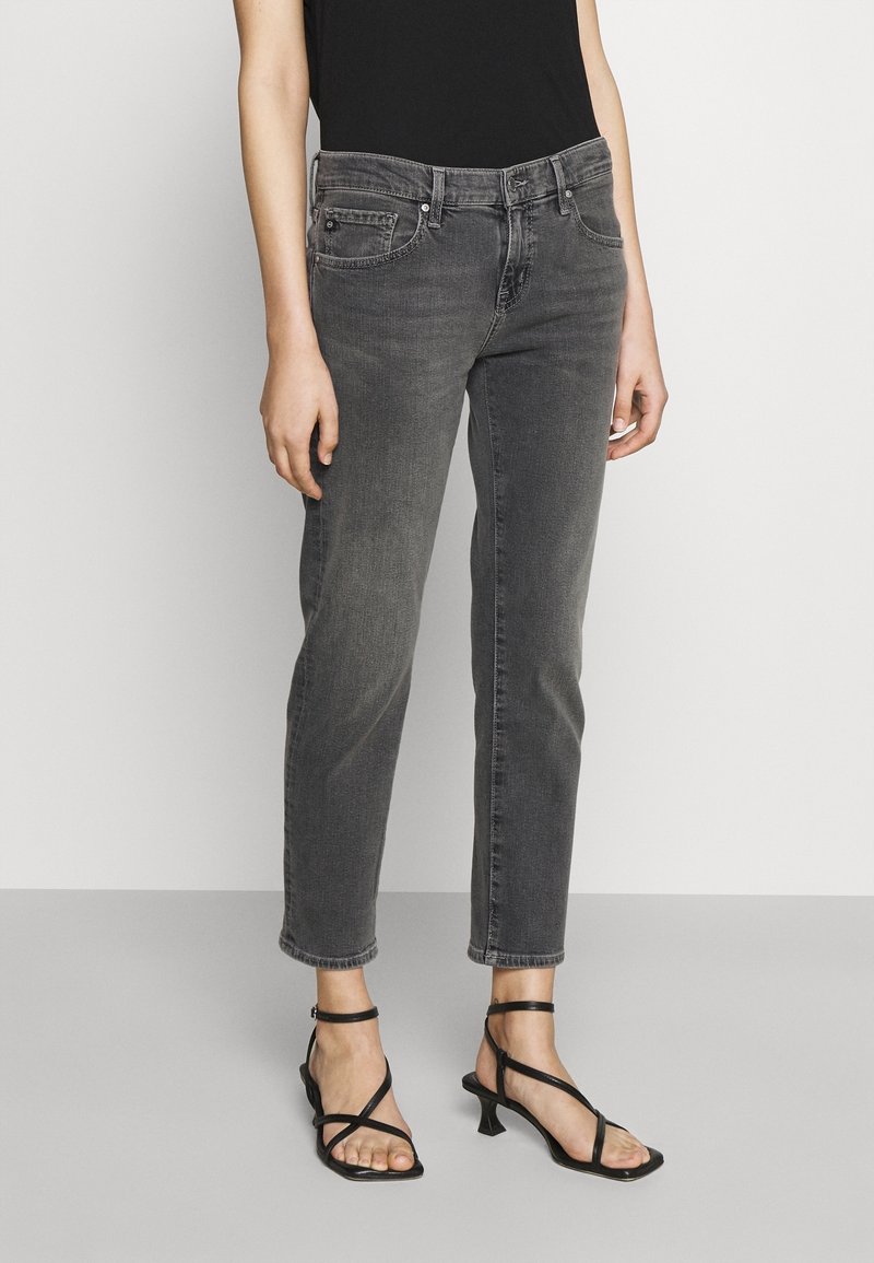 Szare jeansy dżinsowe o średnim stanie i prostych nogawkach, z standardowymi kieszeniami i lekko wyblakłą fakturą. W zestawie z czarnymi sandałami na paski na obcasie.