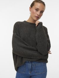 Maglione grigio scuro a maglia con collo tondo, maniche larghe e vestibilità rilassata, abbinato a jeans in denim blu. Texture liscia, design minimale.