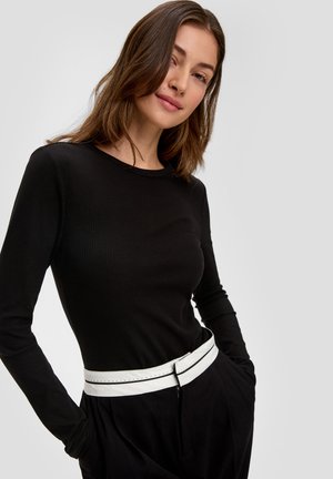 Black ribbed long-sleeve top paired with high-waisted black pants featuring a white belt with stitching detail, against a neutral background.