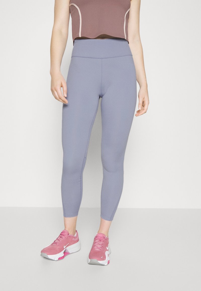 Leggings azzurri chiari a vita alta, realizzati in materiale elasticizzato. Abbinati a scarpe da ginnastica rosa con dettagli bianchi e logo.