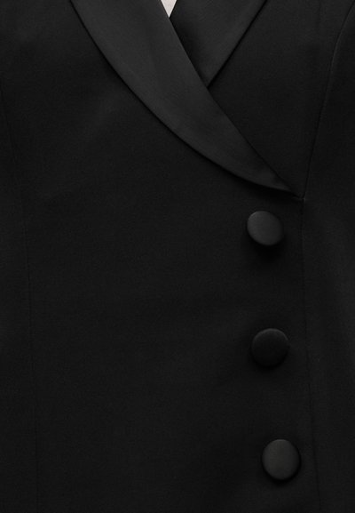 Fekete blézer selyem hajtókával, strukturált kialakítással, elöl három anyaggal bevont gombbal. Végig sima, matt textúrájú.