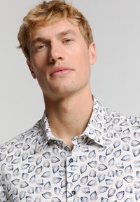 Overhemd met kraag van lichtgewicht stof met een witte basis en een blauw schelp patroon. Voorzien van donkere knopen en een gestructureerde kraag.