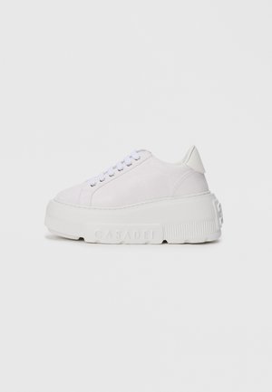White platform sneaker with laces, thick textured sole embossed with "CASADEI," and smooth heel tab, shown in side profile.