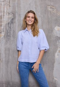 Gestreept overhemd in lichtblauw en wit katoen, met een knoopsluiting aan de voorkant, korte pofmouwen en een licht cropped zoom.